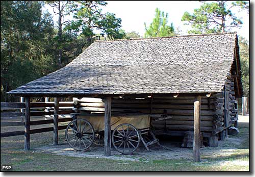 An antique buggy under cover of one of the outbuildings