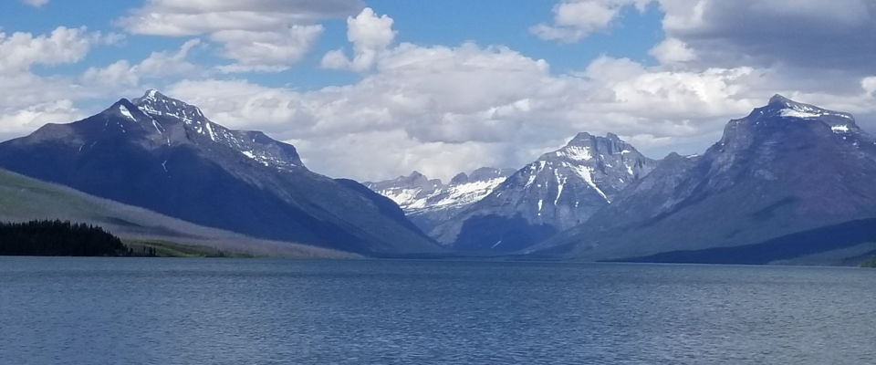 Mountains rise sharply beyond a lake in Glacier National Park in Montana