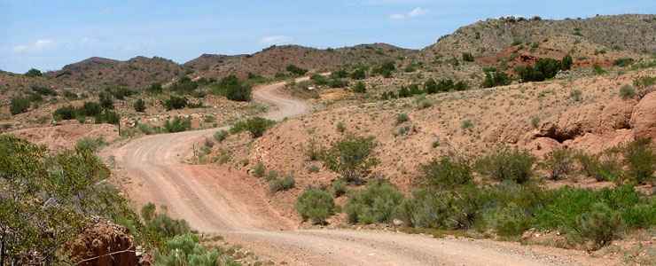 Halfway point on the Quebradas Backcountry Byway: the road winds up a hill surrounded by sparse vegetation in the northern Chihuahuan desert