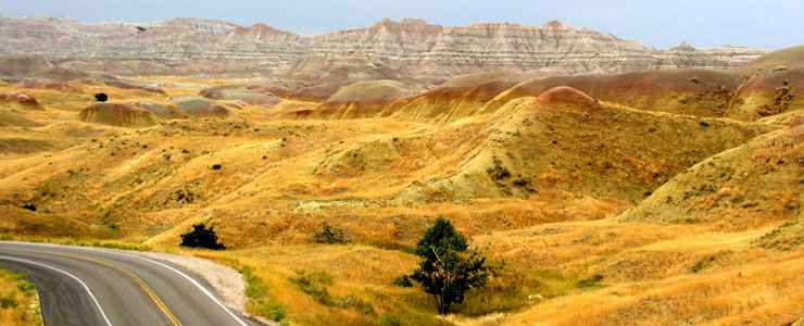 Grassy, rolling hills and badlands in the distance along the Badlands Loop Scenic Byway